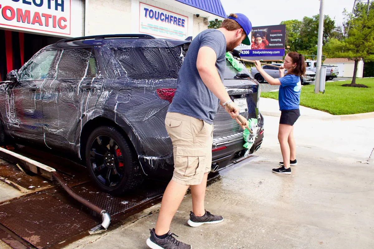 Customers hand-washing an SUV in a Water Works self-serve bay